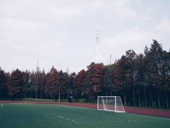 Soccer goal on field by trees against clear sky