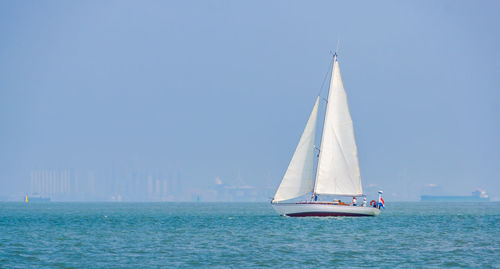 Sailboat sailing on sea against clear sky