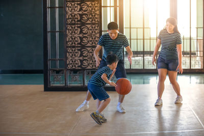 Parents playing basketball with son in court