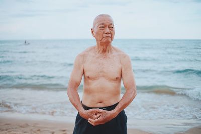 Portrait of shirtless man standing at beach