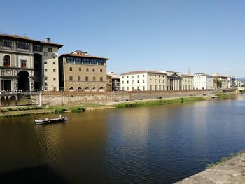 Buildings by river against clear sky