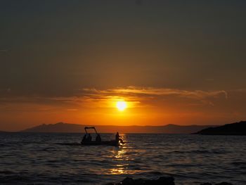 Silhouette boat in sea against sky during sunset
