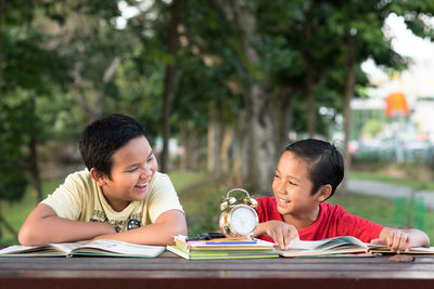 Siblings studying on table in park