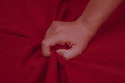 Close-up of hand on red sheet