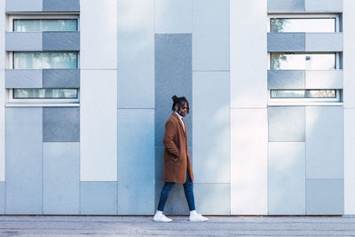 Full length of woman standing on footpath against building