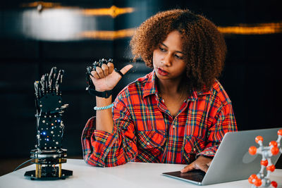 Portrait of woman using mobile phone while sitting on table