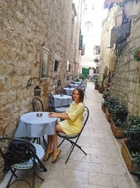 Portrait of woman sitting on chair against building