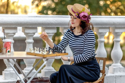 Portrait of young woman standing by railing