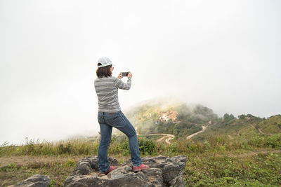 Full length of photographer photographing on mountain against sky