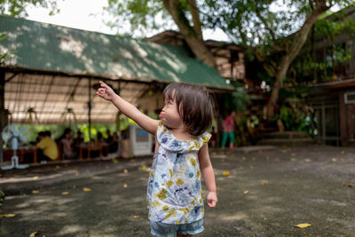 Cute toddler girl gesturing while standing on footpath