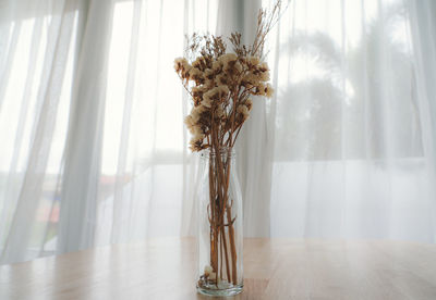 Close-up of flower vase on table against window