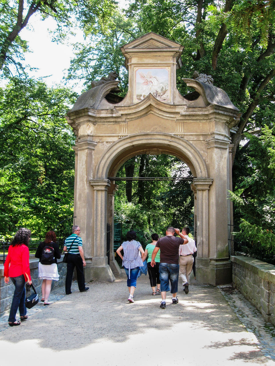 group of people, architecture, tree, plant, men, full length, women, adult, walking, built structure, nature, day, gate, arch, travel destinations, building exterior, shrine, rear view, tourism, city, travel, medium group of people, outdoors, lifestyles, entrance, leisure activity, group, the past, building, tourist, history, person, casual clothing, footwear, togetherness, child