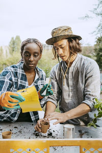 Young female environmentalist looking at packet standing by man in farm