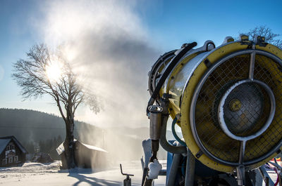 Snow making in ski area against sky during winter