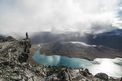 Hiker standing on mountain against sky