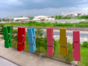 Close-up of multi colored clothespins hanging on clothesline against sky