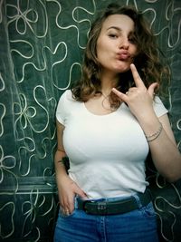 Portrait of beautiful young woman standing against wall