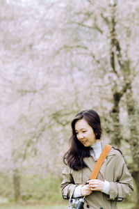 Portrait of young woman looking away while standing outdoors