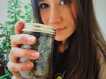 Close-up portrait of a young woman holding jar