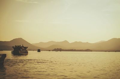 Boats in sea at sunset