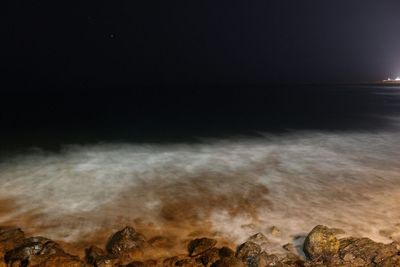 Close-up of illuminated beach against sky at night