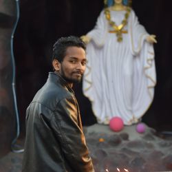 Portrait of young man standing against statue in church