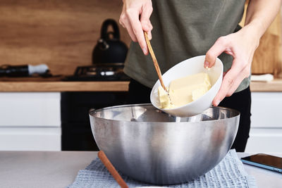 Hands put a butter in bowl. cooking recipe