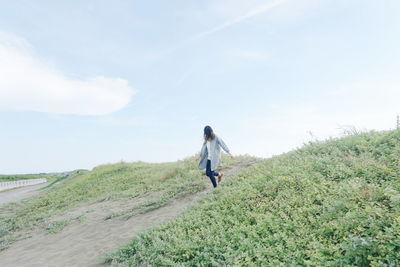 Low angle view woman moving down on hill against sky