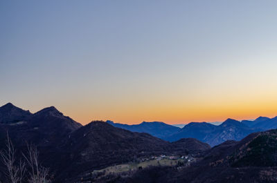 Scenic view of silhouette mountains against clear sky during sunset