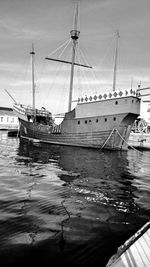 Sailboats moored on harbor against sky