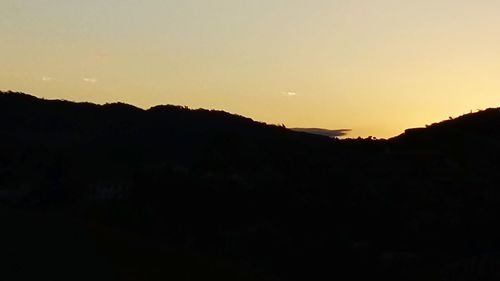 Scenic view of silhouette mountains against clear sky at sunset