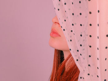 Close-up portrait of woman against pink background