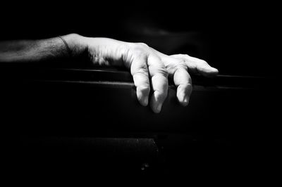 Close-up of cropped hand against black background