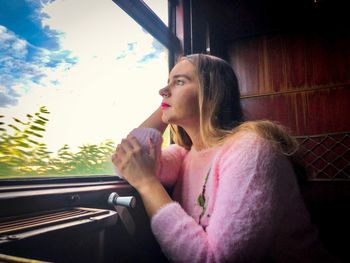 Portrait of young woman looking through window