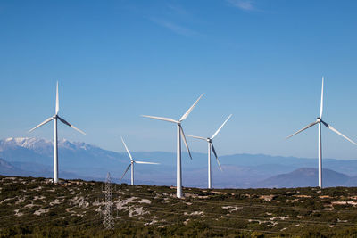 Low angle view of windmills against clear sky