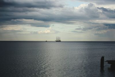 Boat sailing in sea against cloudy sky