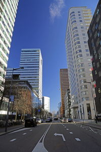 City street by modern buildings against sky