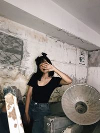 Portrait of young woman standing against wall