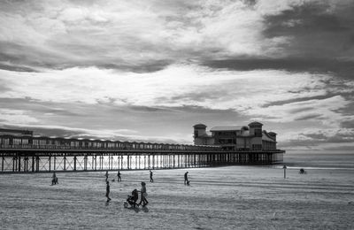 People at beach against cloudy sky