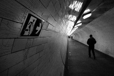 Rear view of man walking in illuminated tunnel