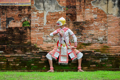 Full length of man standing against brick wall