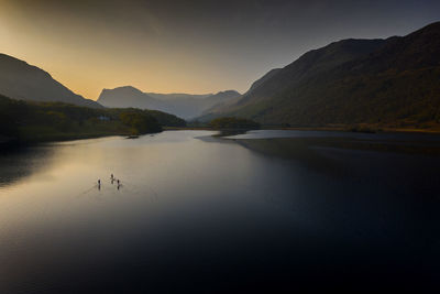 Paddle boarders sail across crummock water, lake district