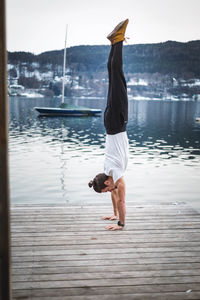 Rear view of man on pier over lake against sky