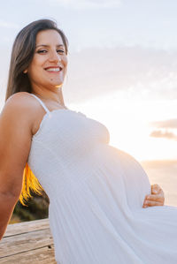 Portrait of smiling young woman standing against sky