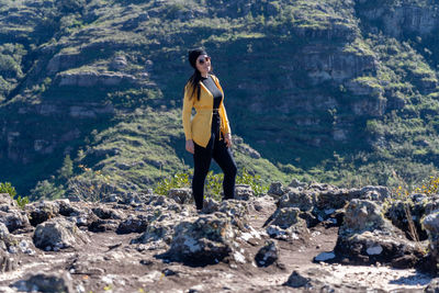 Full length of young woman standing on rock