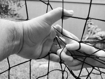 Close-up of hand holding chainlink fence