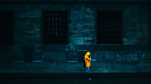 Full length rear view of man standing on wet street