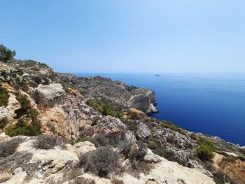 Rock formations by sea against clear blue sky