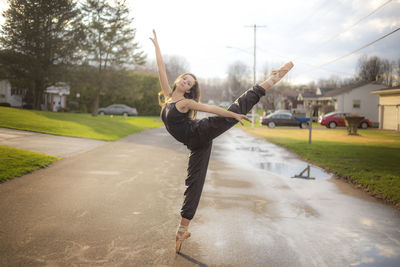 Full length of young woman posing against sky