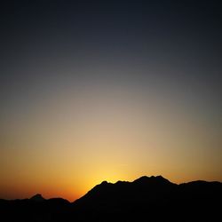 Scenic view of silhouette mountains against clear sky during sunset